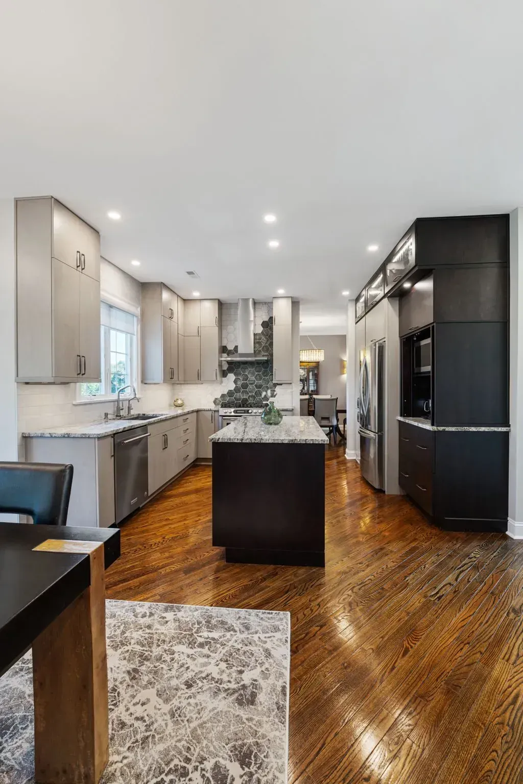 Modern open-concept kitchen with dark island, white cabinetry, and glossy wood floors In Bucks County PA