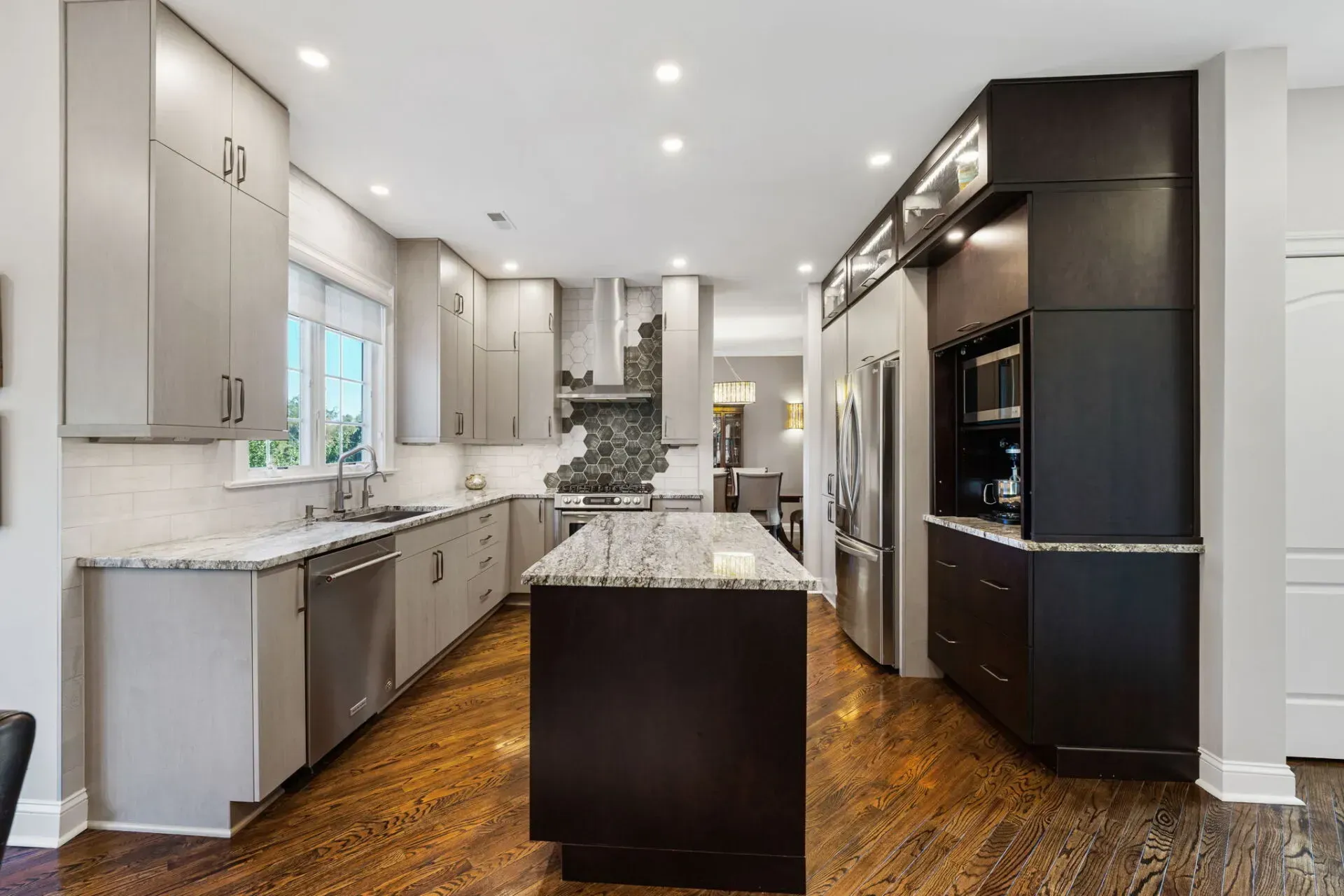 Modern white kitchen with dark island, granite countertops, hardwood floors, and stainless steel appliances In Bucks County PA