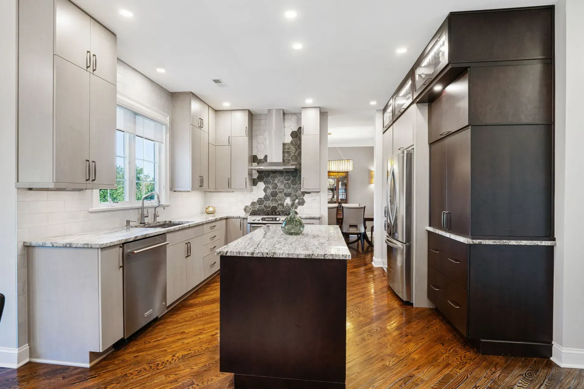 Bright modern kitchen with white cabinets, marble island, dark refrigerator, and wood floors In Bucks County PA