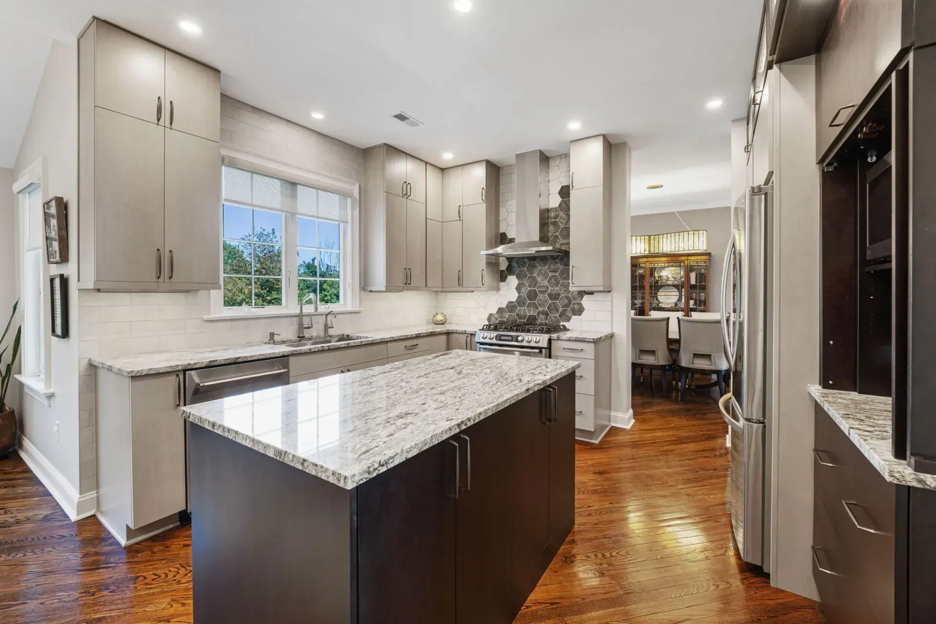 Bright modern kitchen with granite island, white cabinets, hardwood floors, and stainless appliances In Bucks County PA