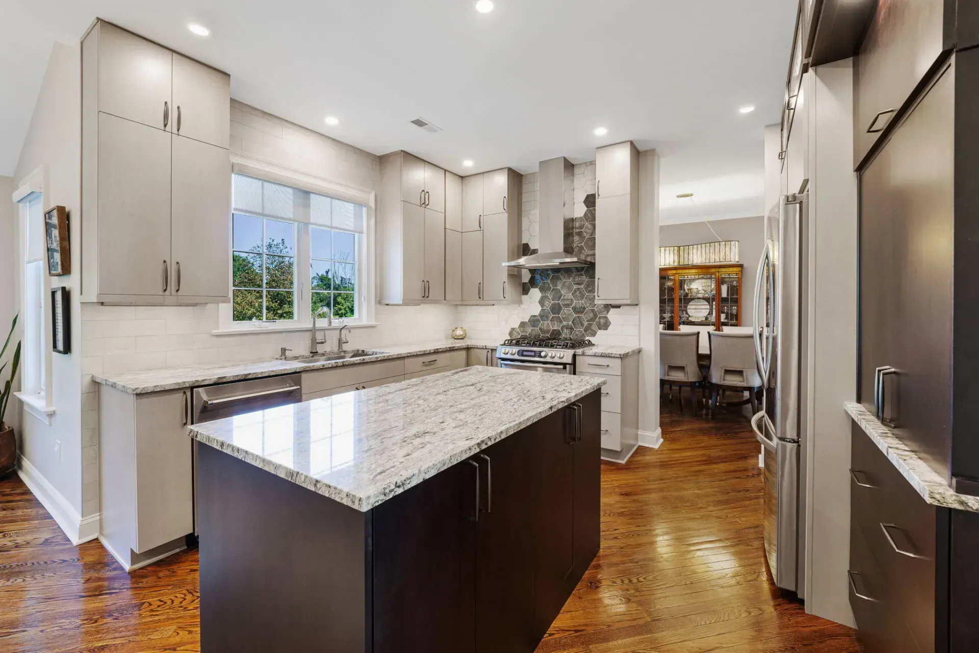Modern kitchen with granite island, white cabinets, stainless appliances, and hardwood floors In Bucks County PA