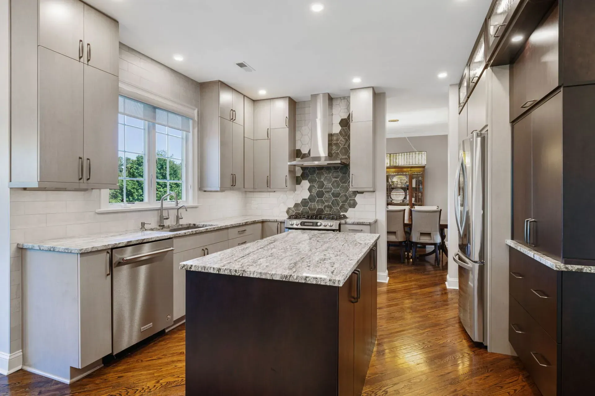 Modern kitchen with gray cabinets, granite island, stainless appliances, and hardwood floors In Bucks County PA
