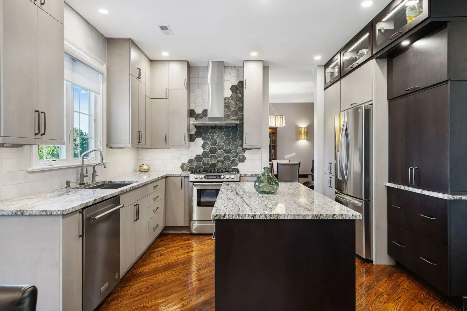 Modern kitchen with dark island, light cabinets, stainless appliances, and wood floors In Bucks County PA