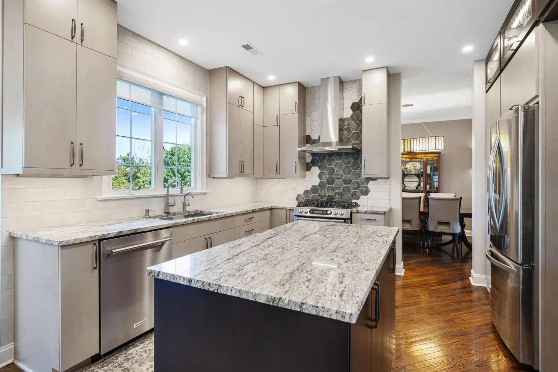 Bright modern kitchen with white cabinets, granite island, stainless appliances, and wood floors In Bucks County PA