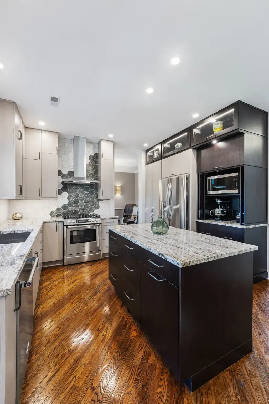Modern kitchen with dark cabinetry, granite island, stainless appliances, and polished wood floors In Bucks County PA