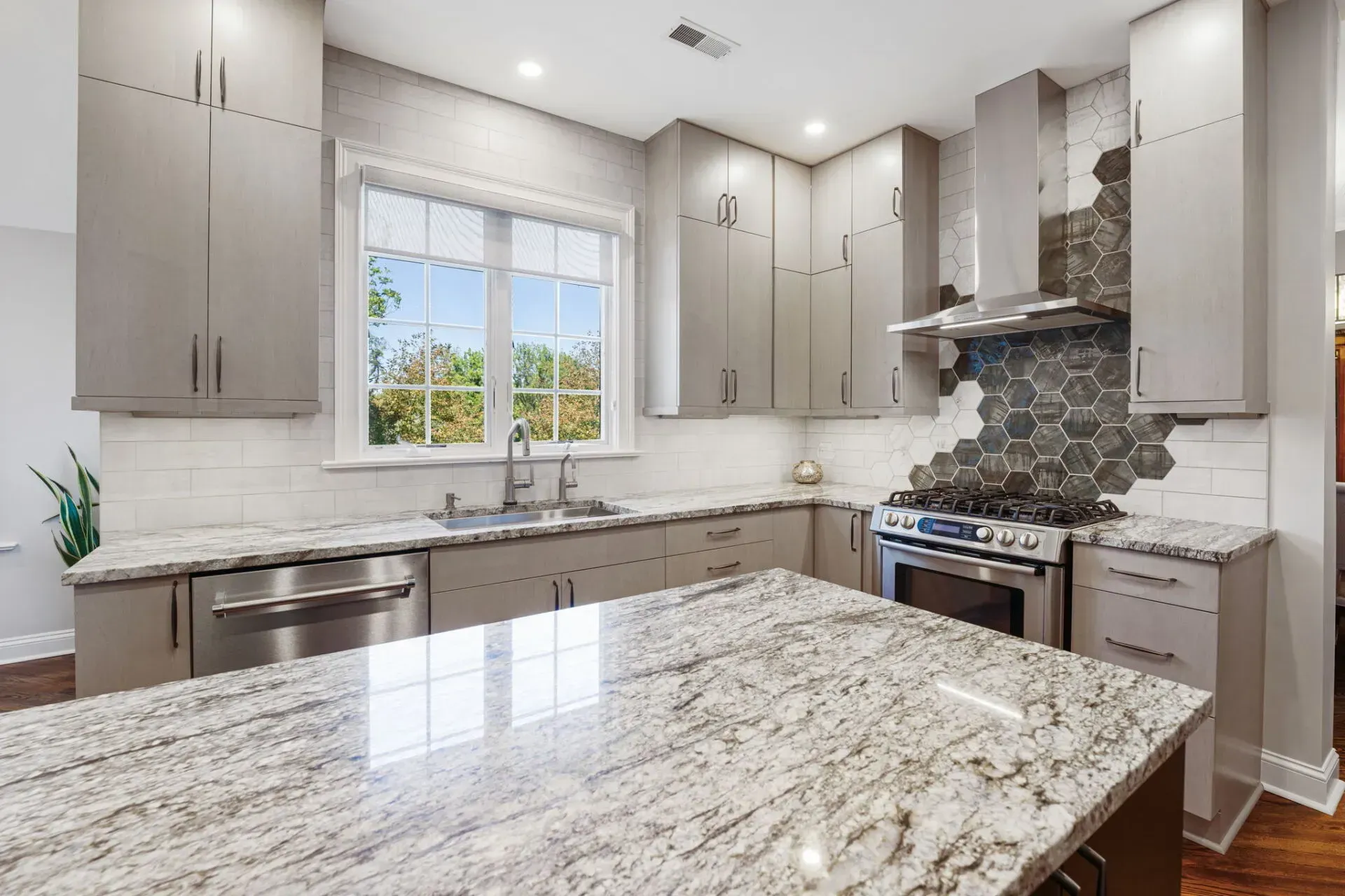 Bright modern kitchen with white cabinets, granite island, stainless appliances, and tiled backsplash In Bucks County PA