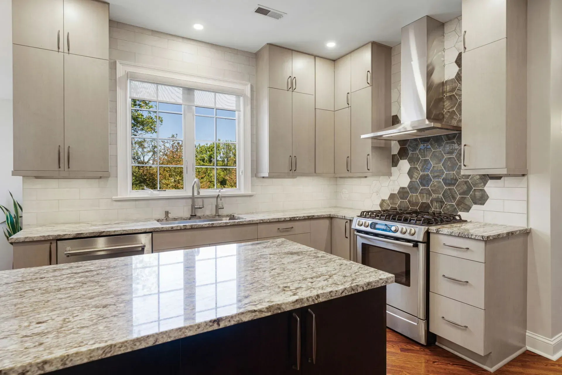 Bright modern kitchen with white cabinets, granite island, and a window over the sink In Bucks County PA