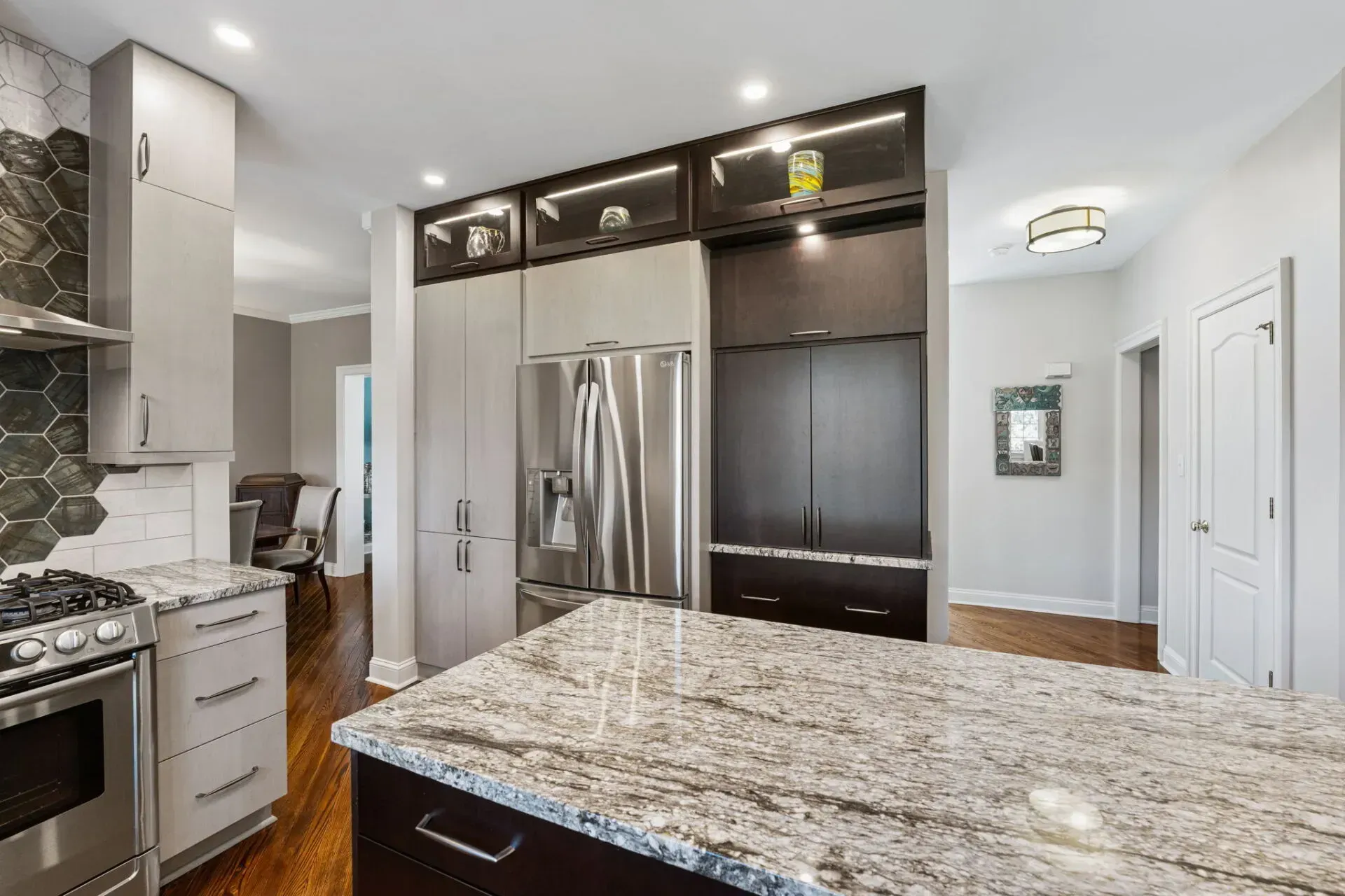 Modern kitchen with granite island, stainless steel refrigerator, and dark cabinetry In Bucks County PA 