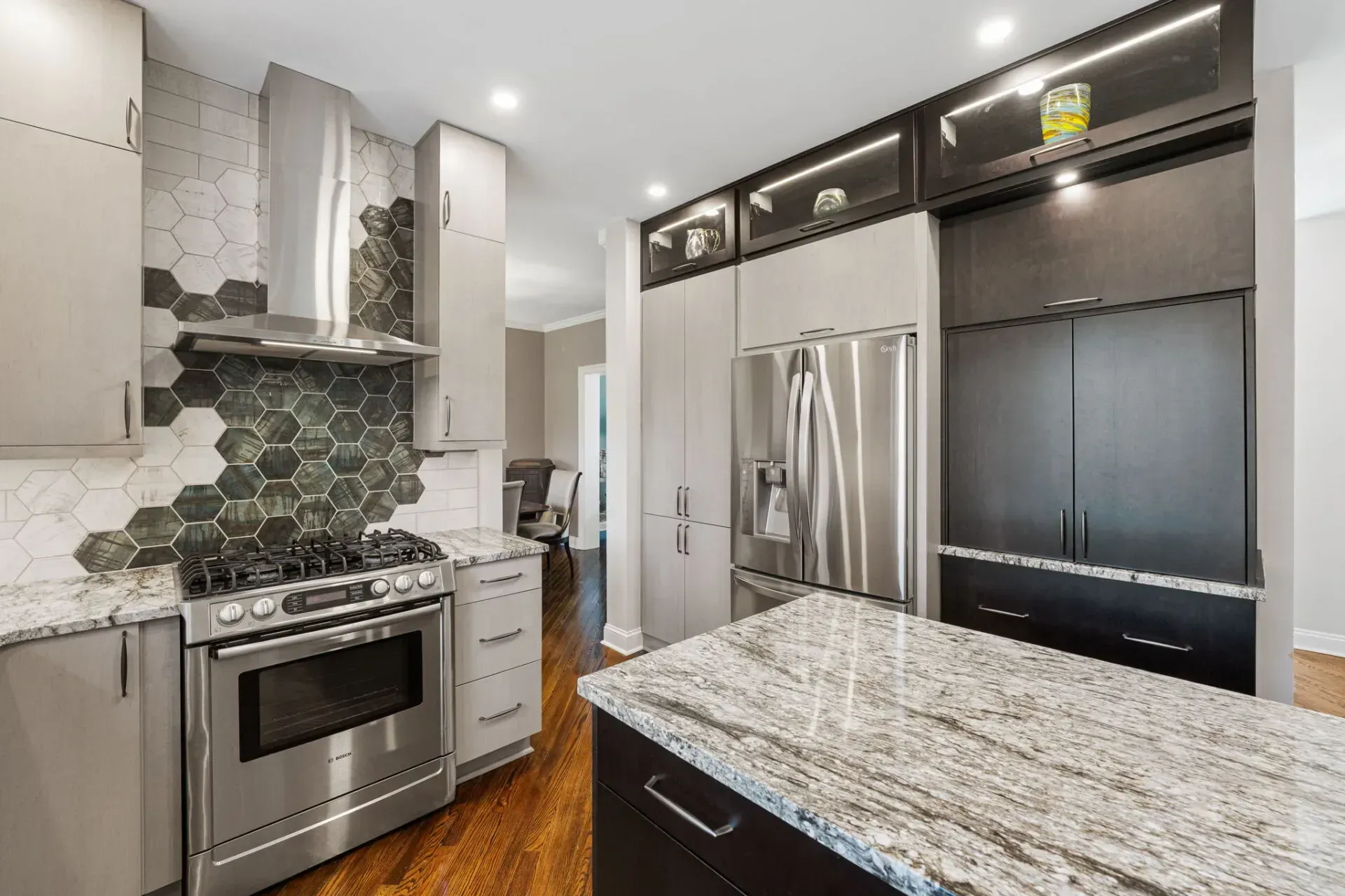 Modern kitchen with stainless steel appliances, granite island, and green hex tile backsplash In Bucks County PA