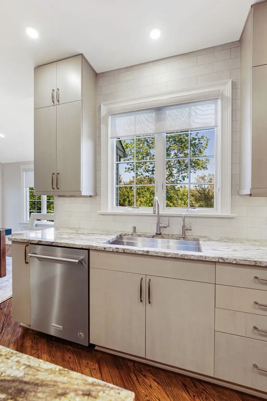 Bright kitchen with white cabinets, stainless dishwasher, marble counter, and window over the sink In Bucks County PA