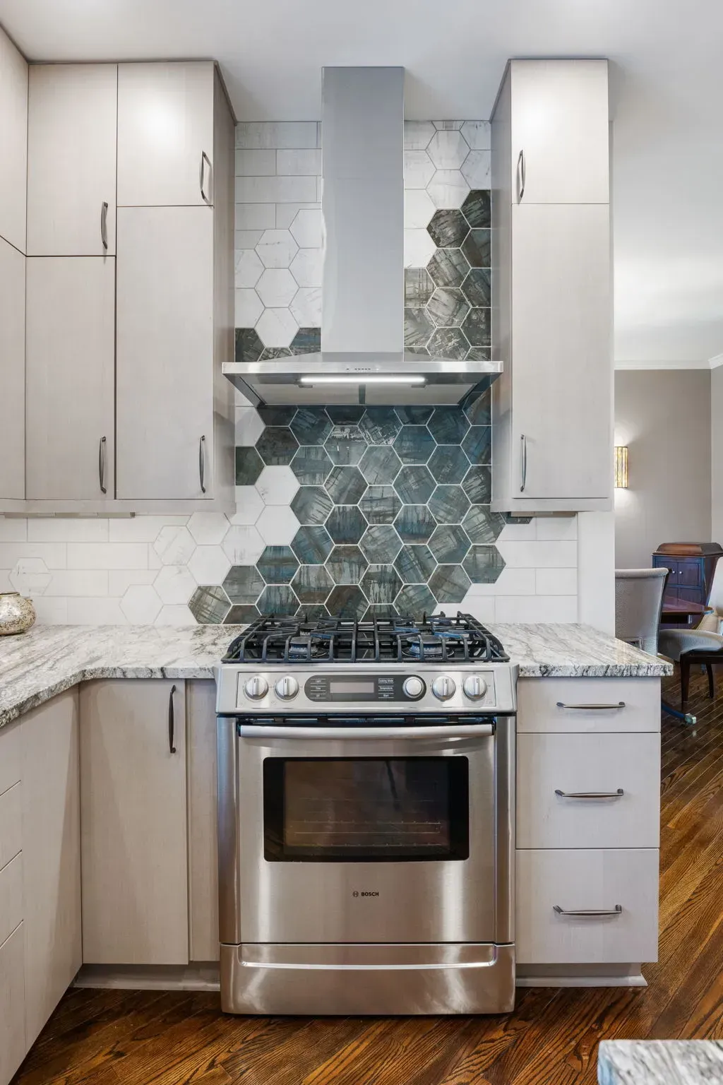 Modern kitchen with stainless stove, white cabinets, and blue hexagon tile backsplash In Bucks County PA