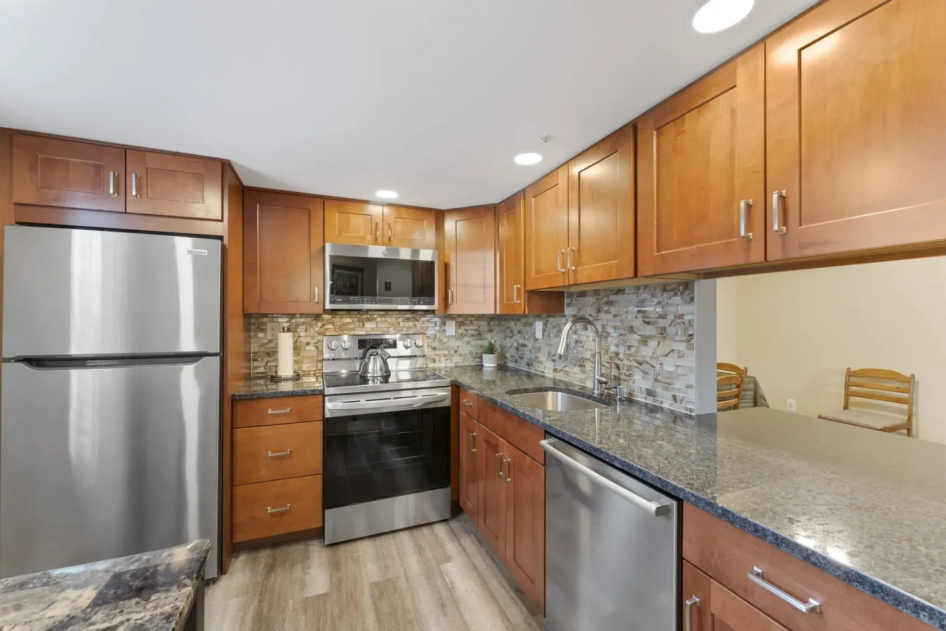 Modern kitchen with wood cabinets, stainless steel appliances, granite counters, and tile backsplash In Bucks County PA