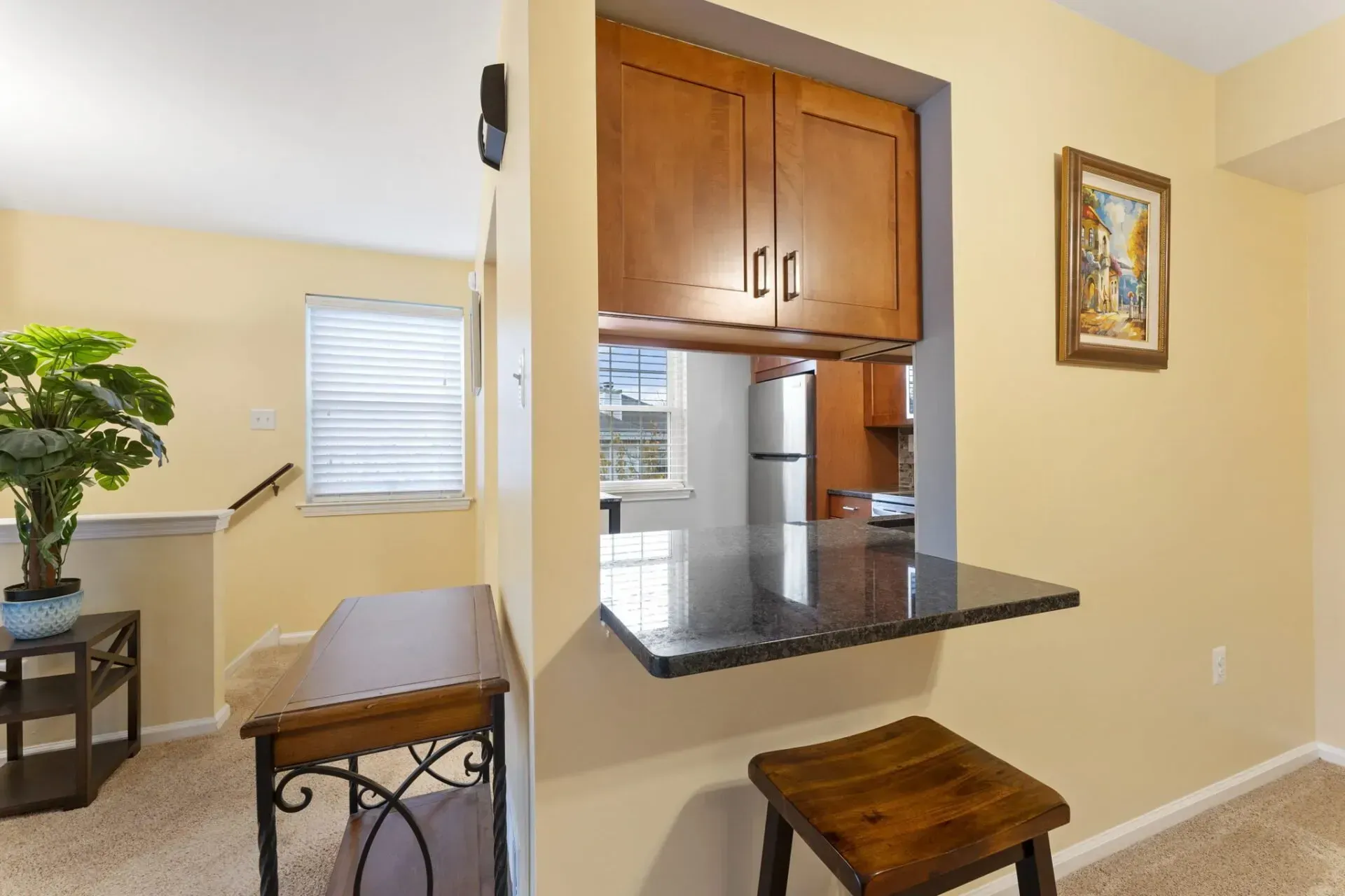 Small home bar nook with wood cabinets, black countertop, and two stools in a beige interior room In Bucks County PA