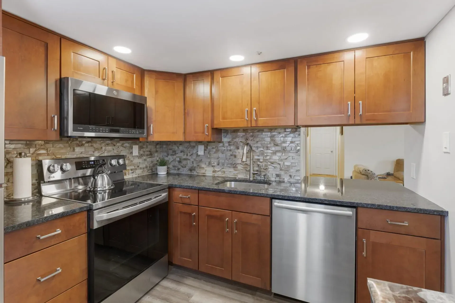 Modern kitchen with wood cabinets, stainless appliances, granite counters, and tiled backsplash In Bucks County PA