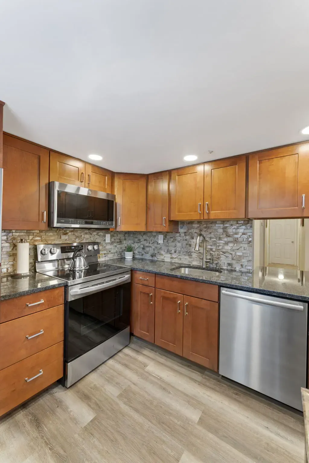 Modern kitchen with wood cabinets, stainless steel appliances, tiled backsplash, and light wood flooring In Bucks County PA