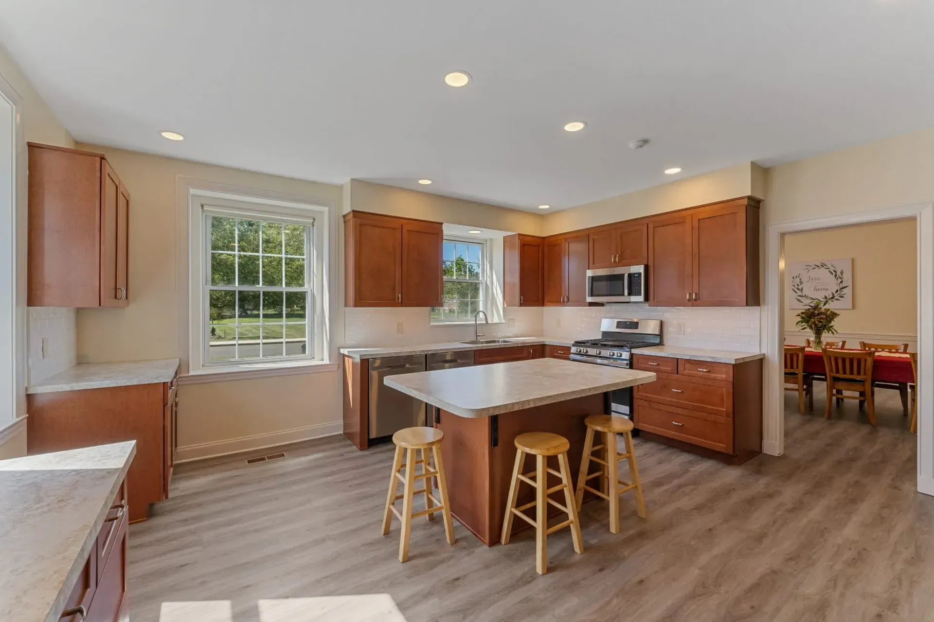 Bright modern kitchen with island, wooden cabinets, stainless appliances, and a dining area visible in the background In Bucks Country PA