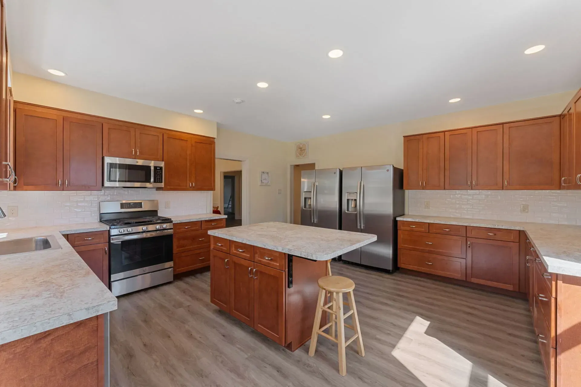 Bright modern kitchen with wooden cabinets, stainless steel appliances, and a central island with a stool  In Bucks County PA