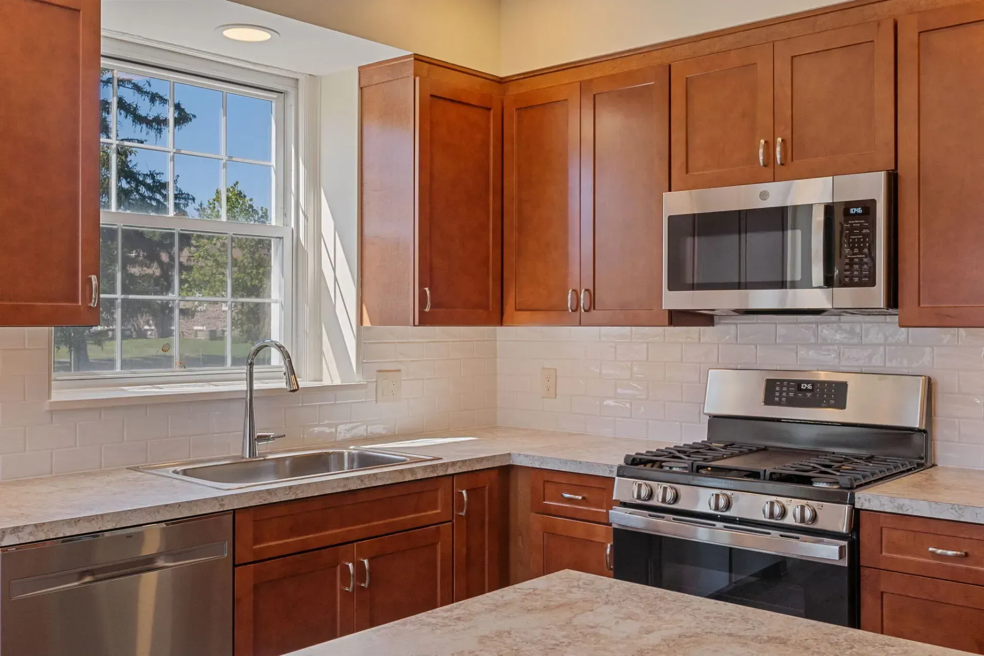 Modern kitchen with wooden cabinets, granite counters, white tile backsplash, and stainless steel appliances  In Bucks County PA