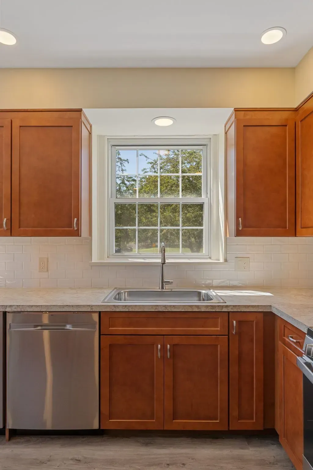 Kitchen with wood cabinets, stainless dishwasher, sink under a window, and granite countertops  In Bucks County PA