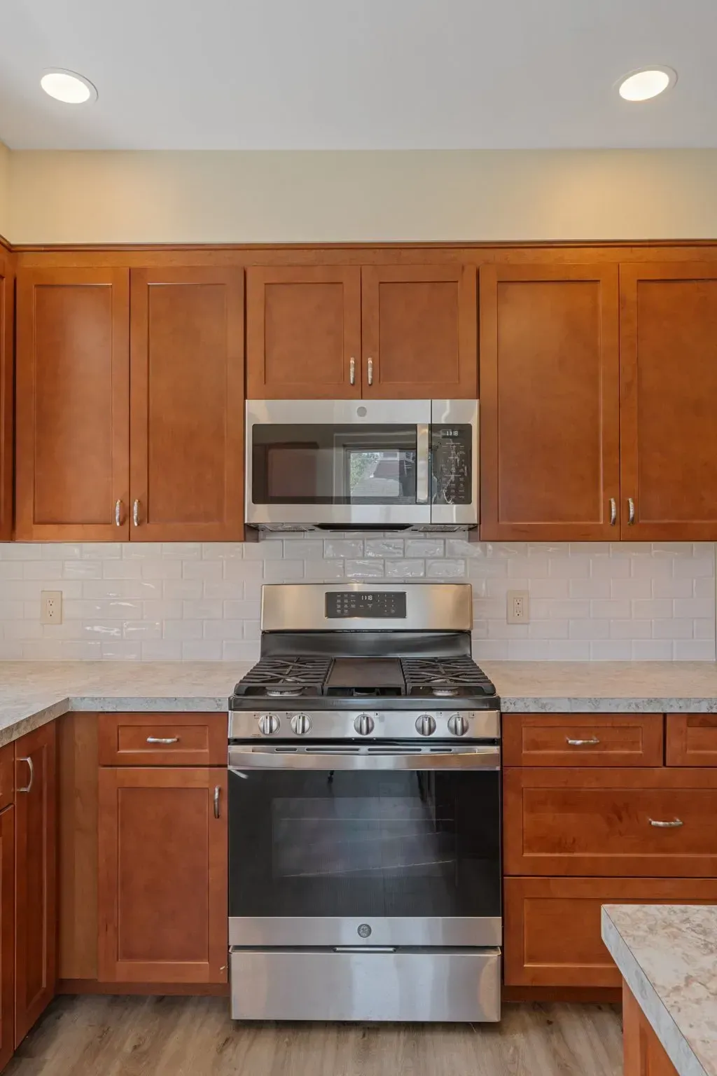Kitchen with wood cabinets, stainless steel microwave and gas range, and granite countertop  In Bucks County PA