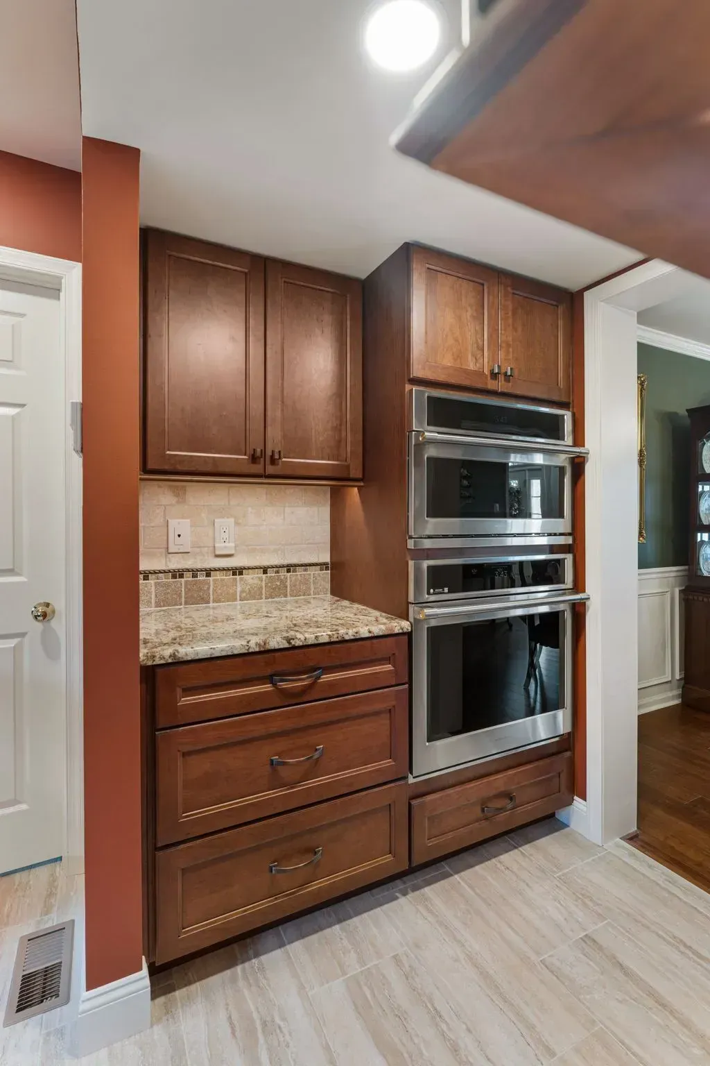 Built-in wood cabinets with double ovens and beige tile backsplash in a kitchen alcove  In Bucks County PA