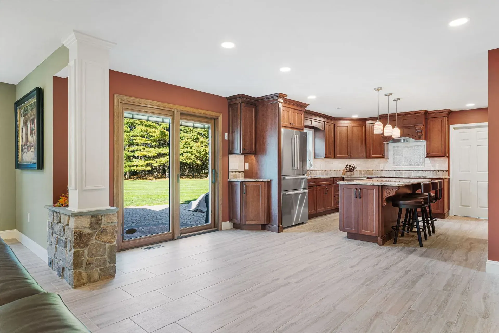 Open-concept kitchen and living area with wood cabinets, island, and sliding glass doors to a backyard