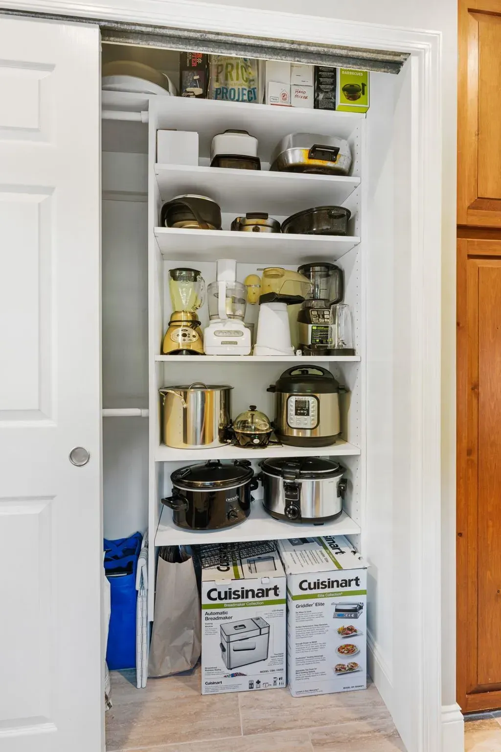 Pantry closet with shelves of kitchen supplies, pots, jars, and paper towel rolls beneath a white shelf  In Bucks County PA