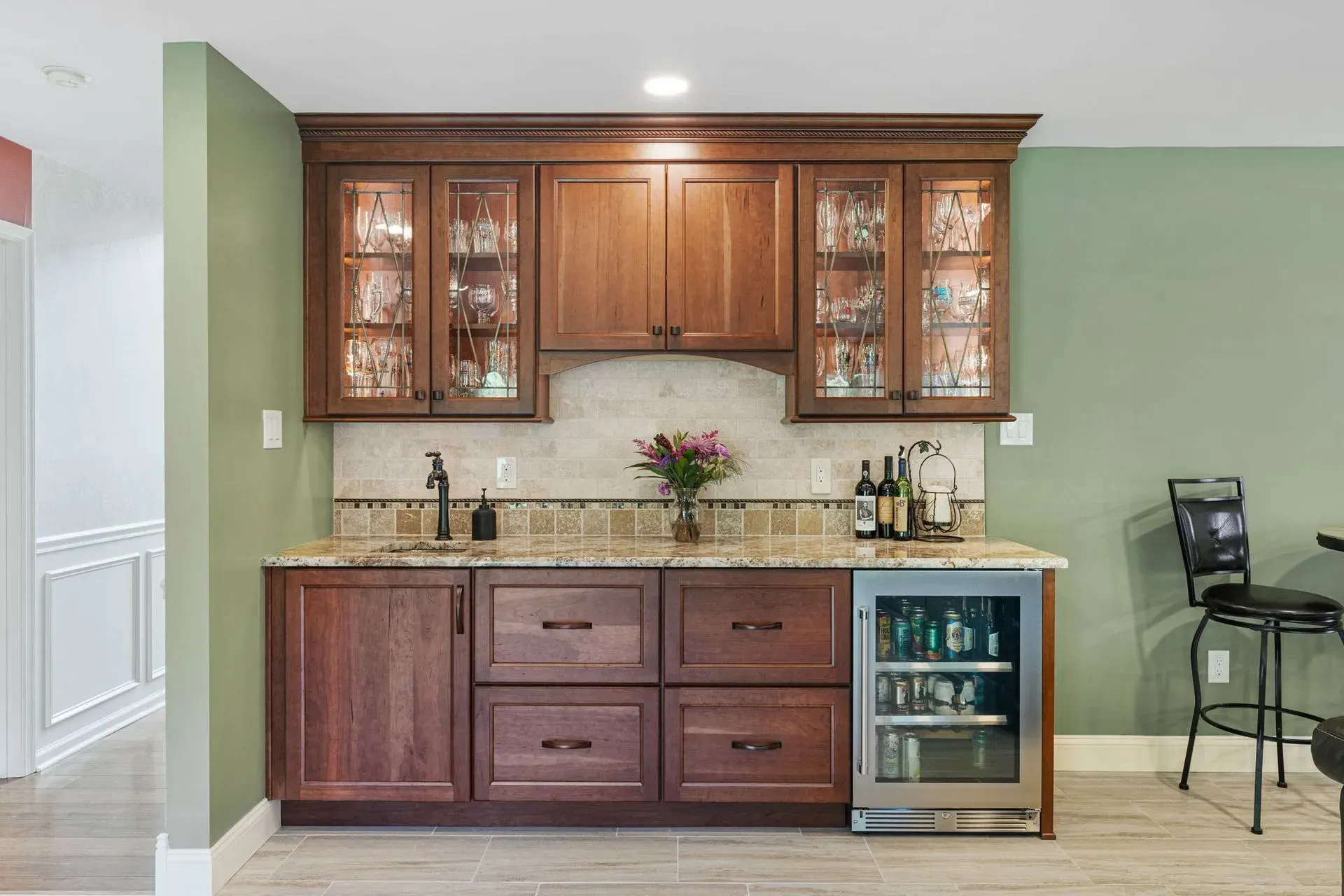Kitchen wet bar with wood cabinets, glass-front uppers, granite countertop, and undercounter wine fridge  In Bucks County PA
