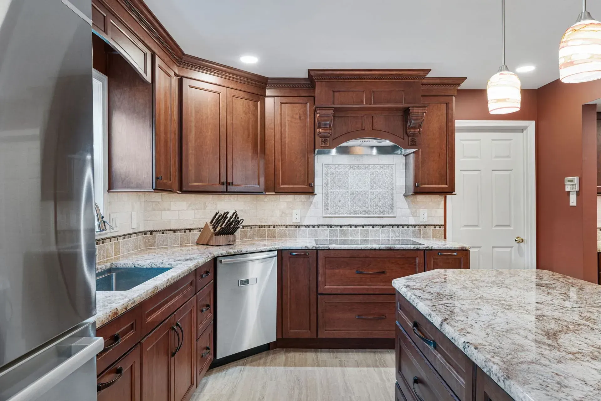 Modern kitchen with dark wood cabinets, granite countertops, stainless steel appliances, and white tile backsplash  In Bucks County PA