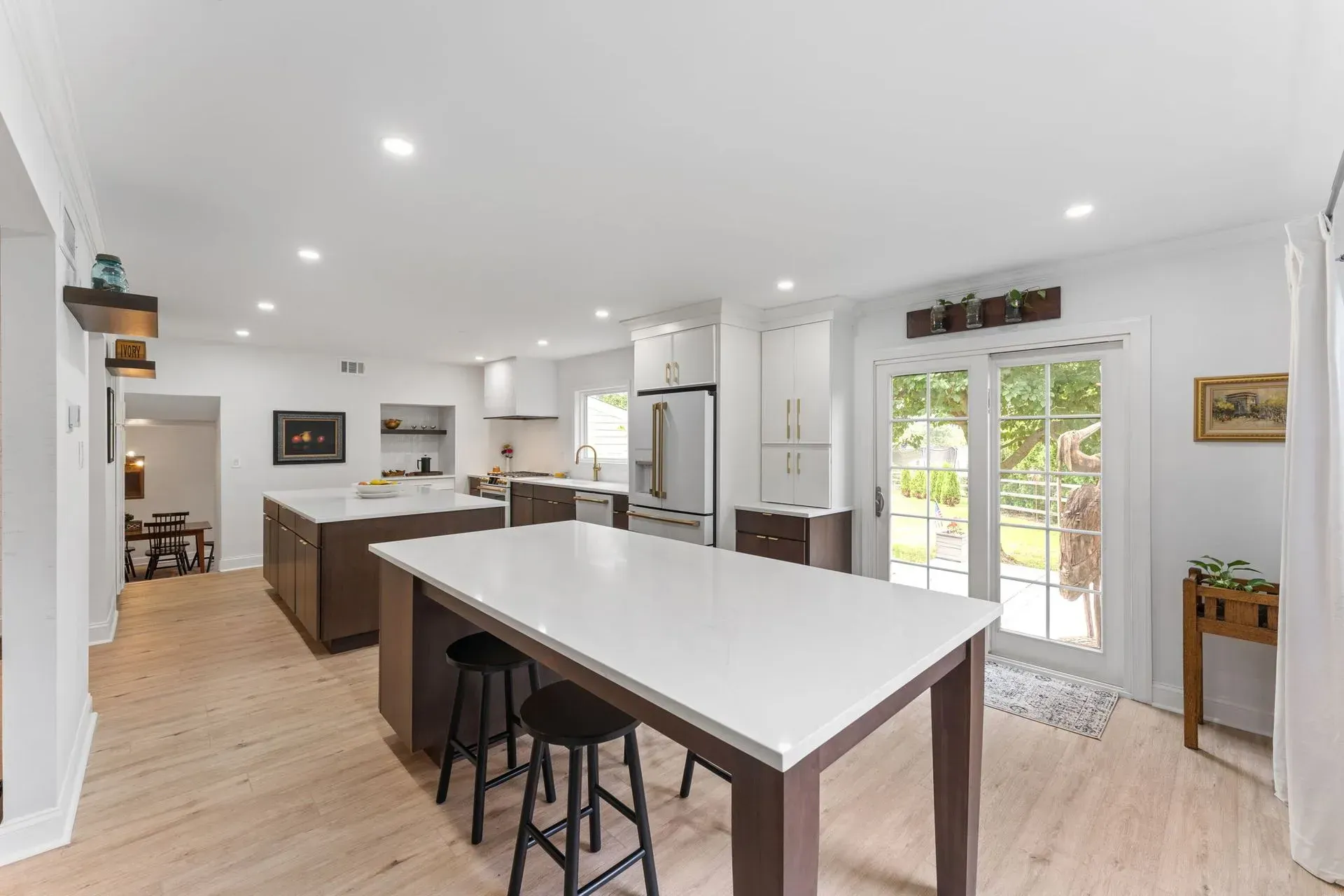 Bright open kitchen with white walls, wood floors, island table, and sliding glass doors to the patio In Bucks County PA