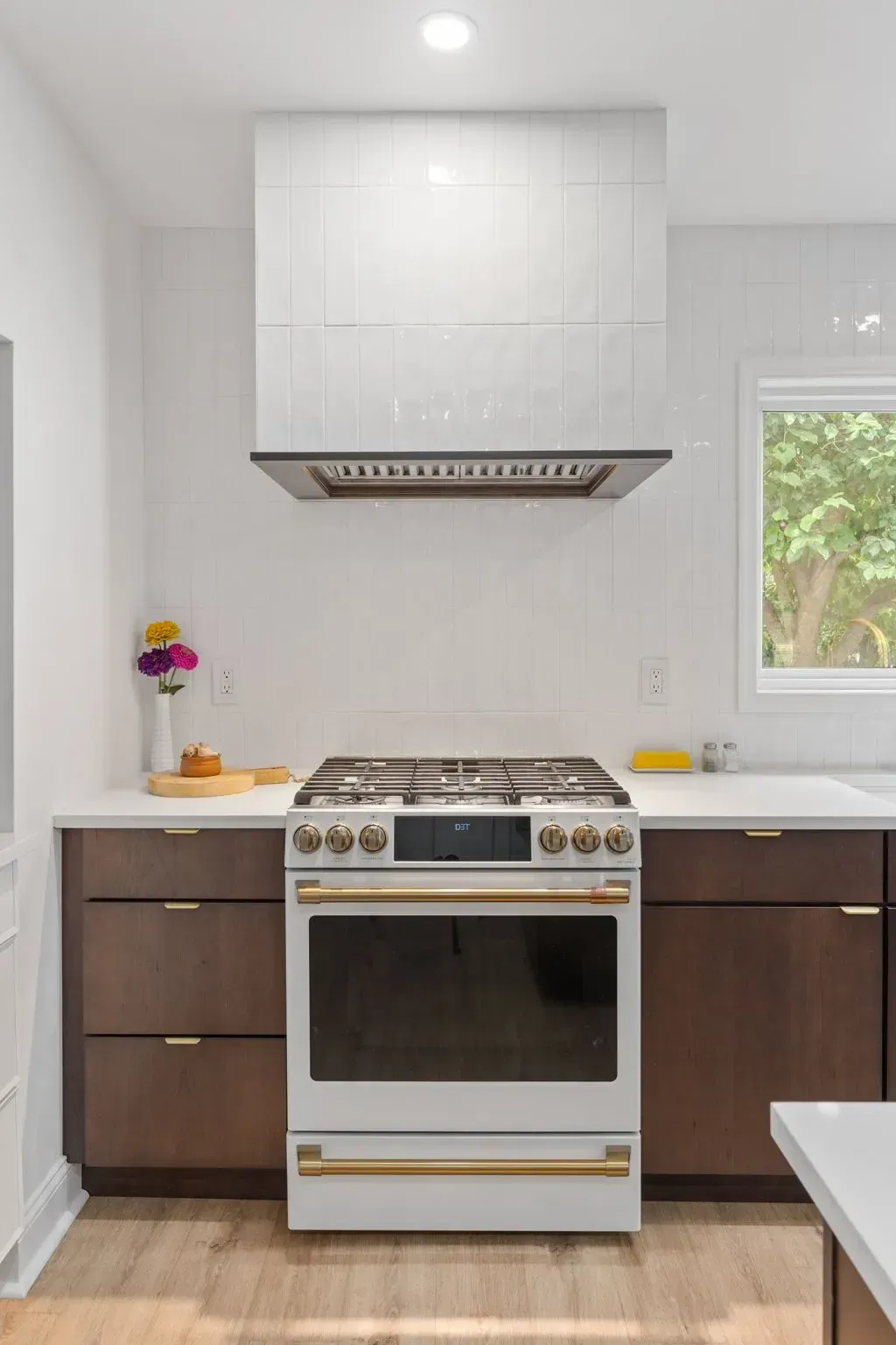 Bright modern kitchen with white cabinets, stainless stove, dark lower cabinets, and a window on the right In Bucks County PA