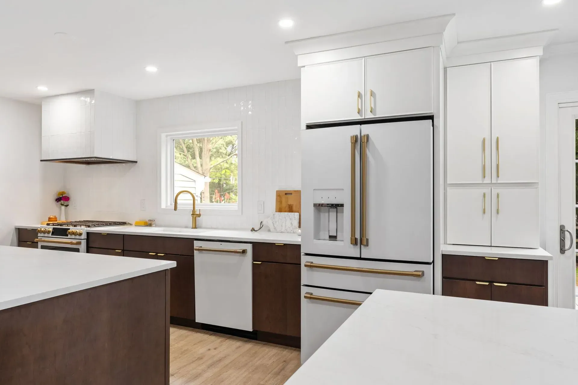 Bright white kitchen with dark wood cabinets, large island, stainless fridge, and window over the sink In Bucks County PA