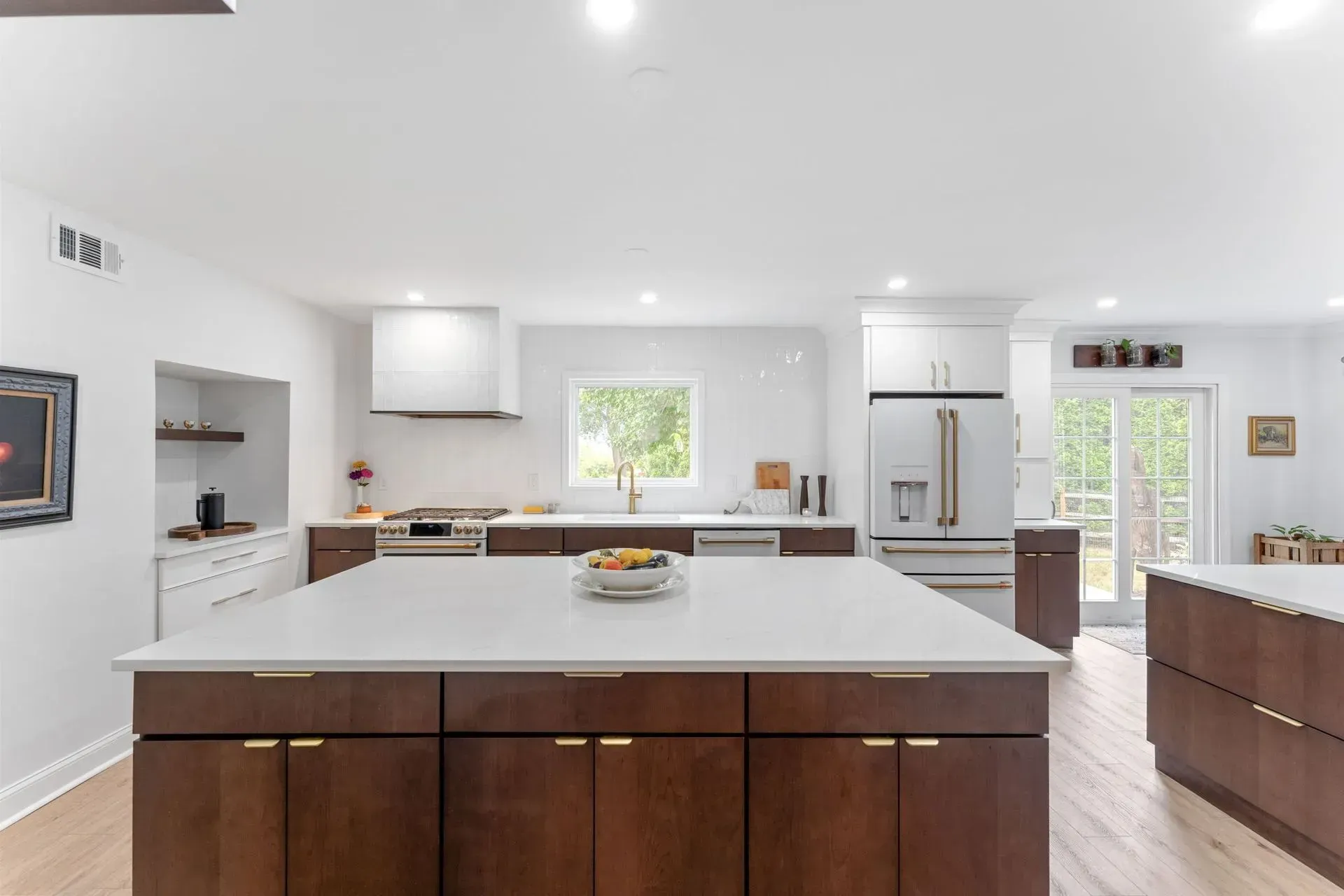 Bright modern kitchen with white countertops, dark wood island, and large windows In Bucks County PA