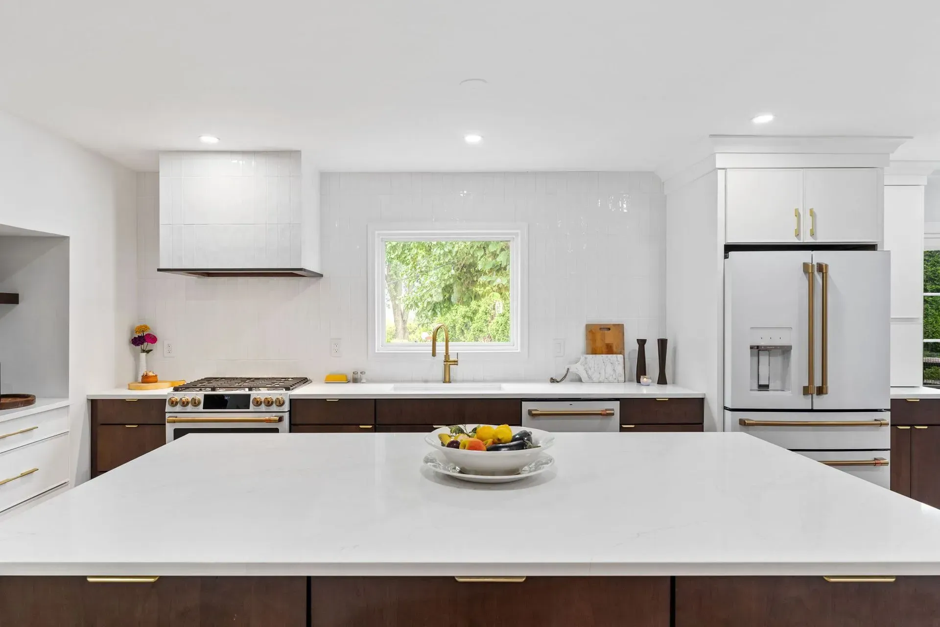 Modern white kitchen with a large island, stainless steel appliances, and a bowl of fruit In Bucks County PA