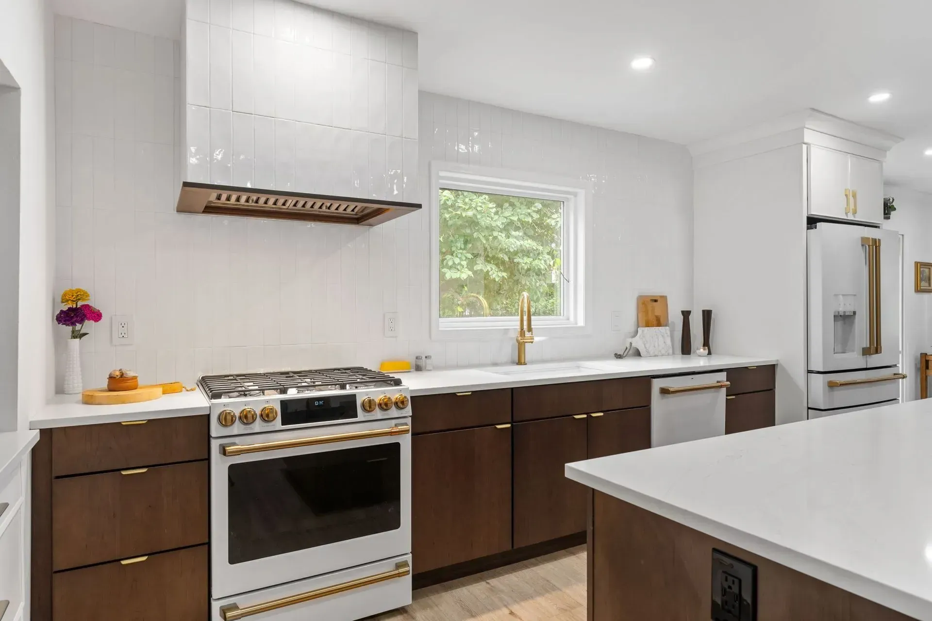 Bright modern kitchen with white cabinets, dark lower cabinets, gas range, and large island counter In Bucks County PA