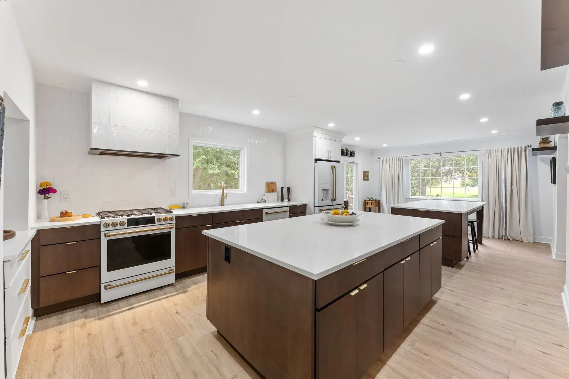 Bright modern kitchen with white cabinets, dark island, wood floors, and large windows In Bucks County PA