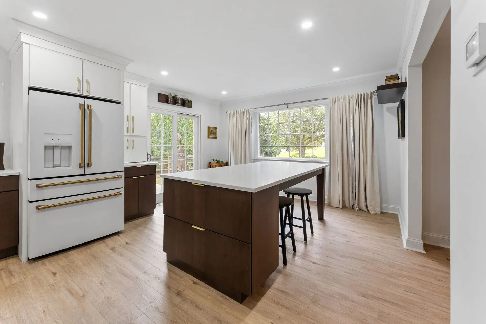 Bright modern kitchen with white cabinets, wood island, and large windows overlooking greenery In Bucks County PA