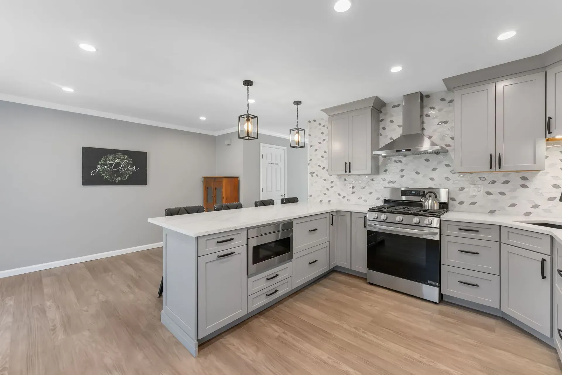 Bright modern kitchen with gray cabinets, white countertops, stainless appliances, and wood floors In Bucks County PA
