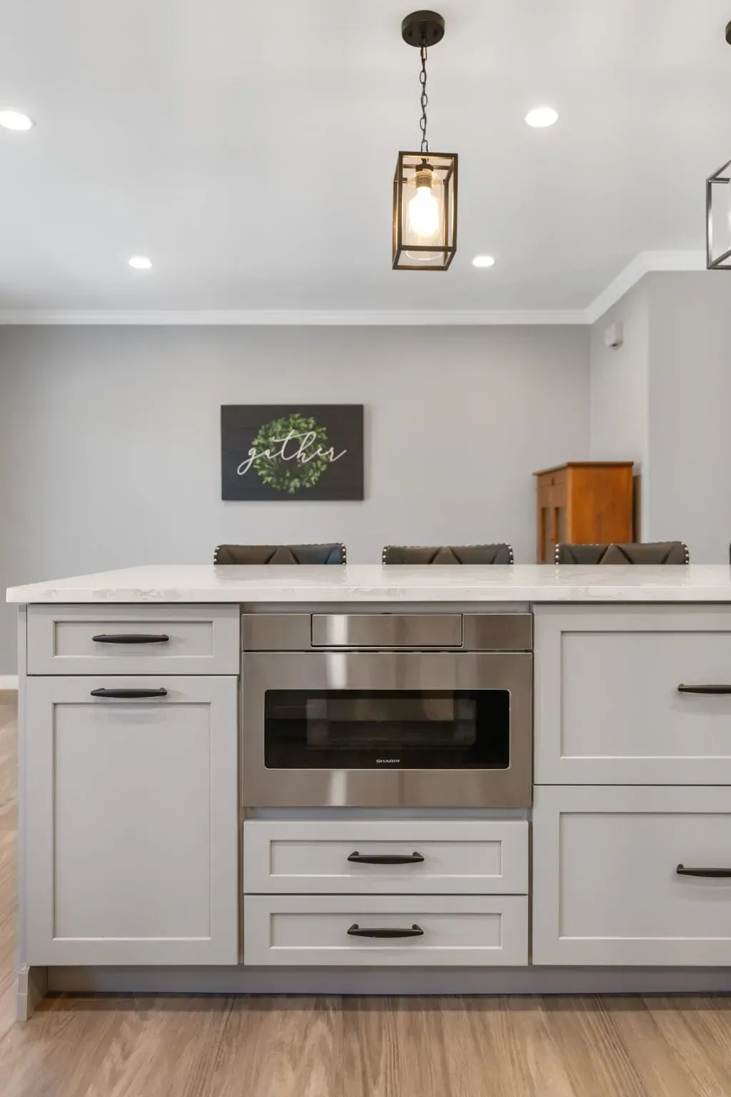 Modern kitchen with gray cabinets, white countertops, stainless oven, and pendant light In Bucks County PA