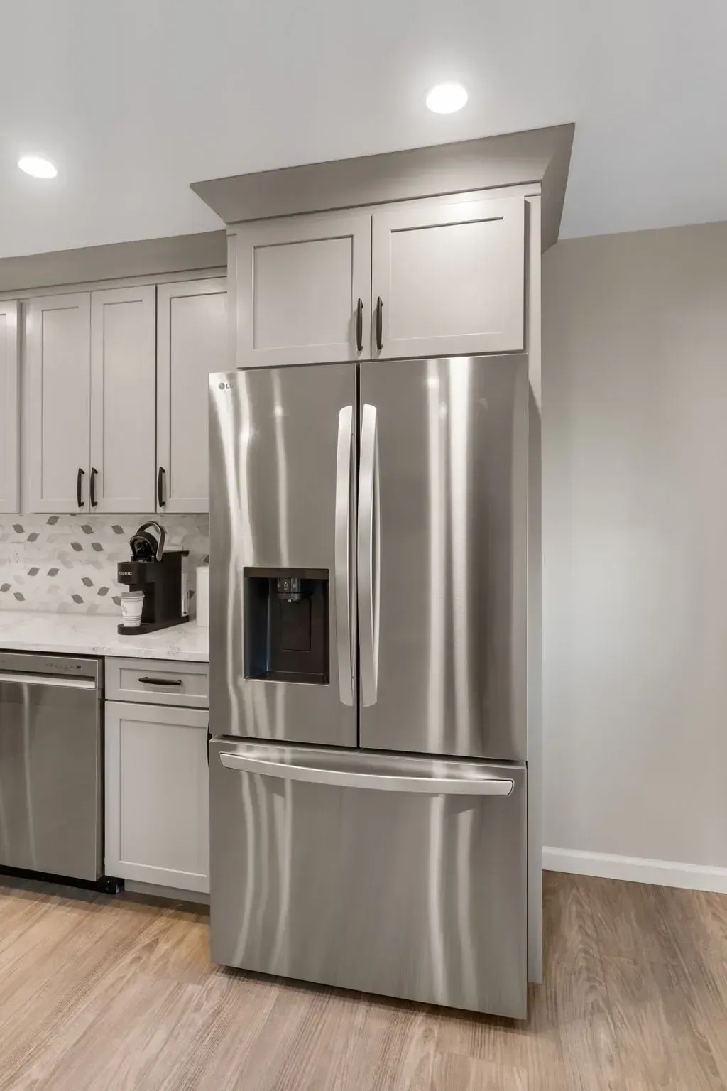 Stainless steel French-door refrigerator in a modern kitchen with white cabinets and wood flooring In Bucks County PA