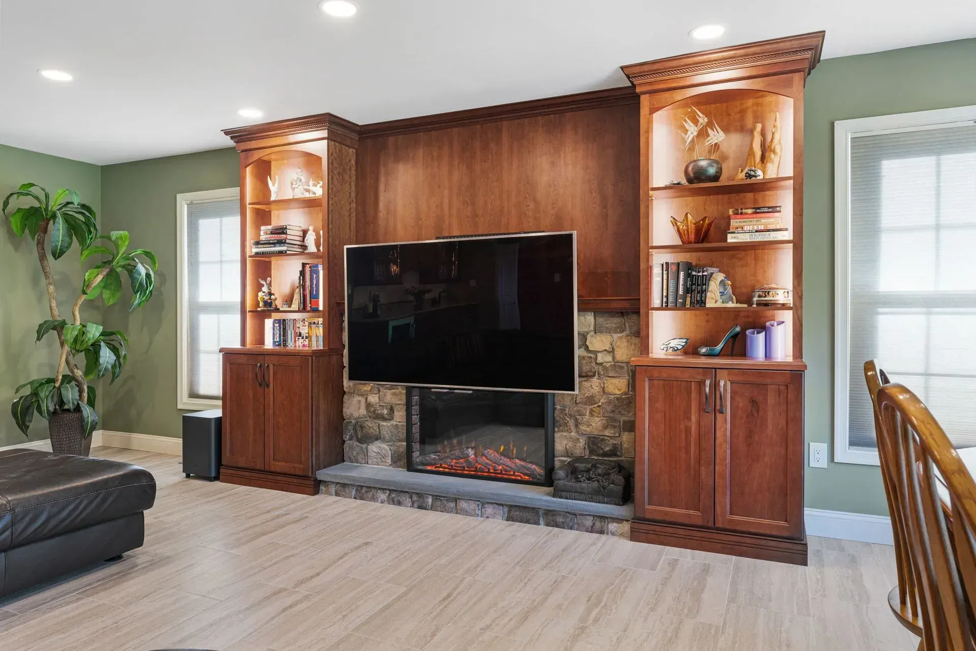 Living room with built-in wood entertainment center, TV, and fireplace against green walls  In Bucks County PA