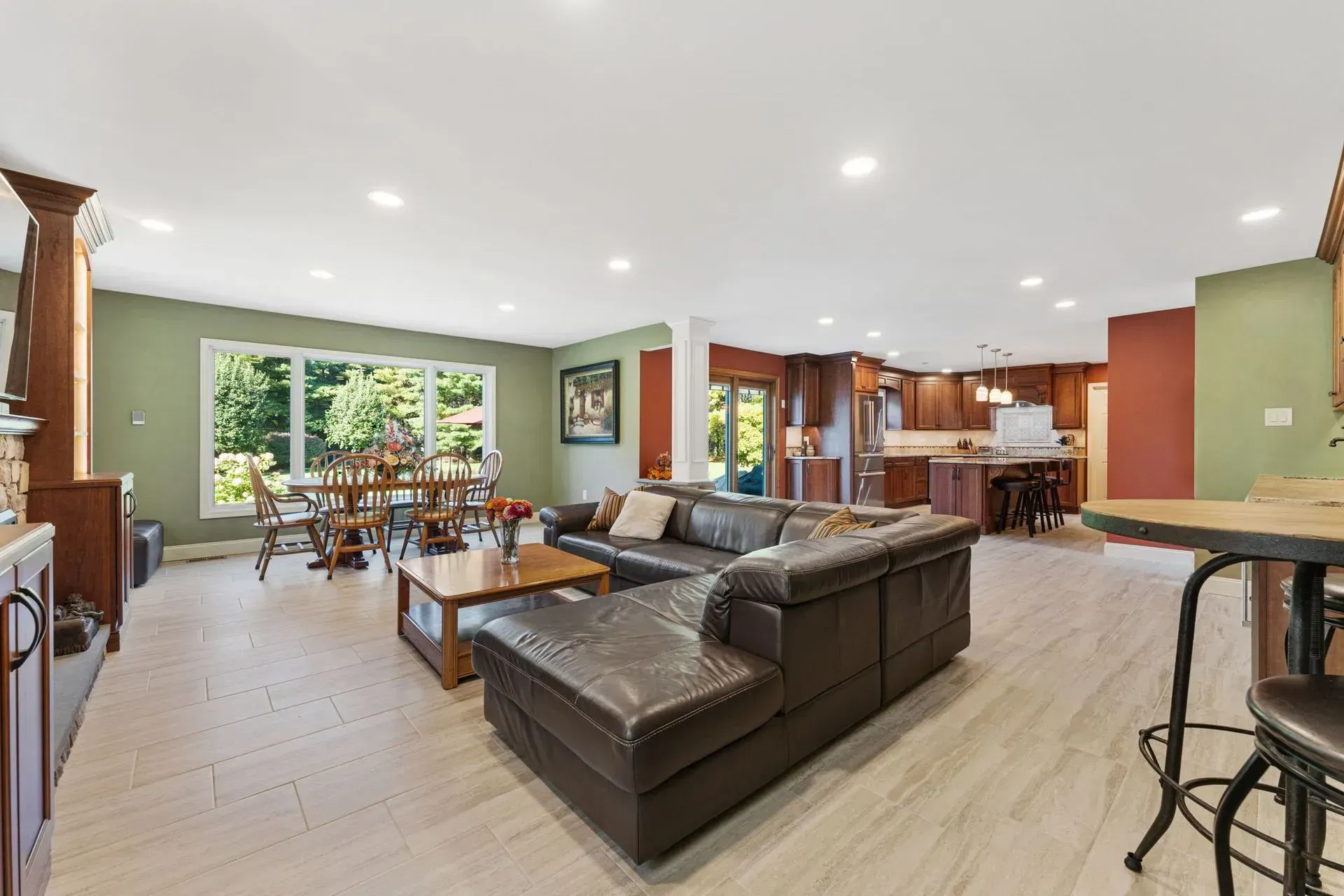 Open-plan living room and kitchen with brown sectional, dining table, and large windows  In Bucks County PA