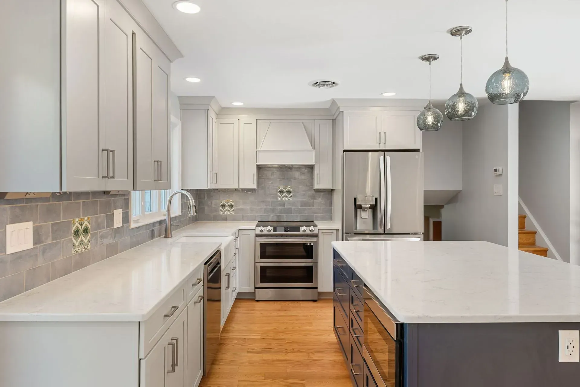 Bright modern kitchen with white cabinets, stainless steel appliances, and a large island with pendant lights  In Bucks County PA