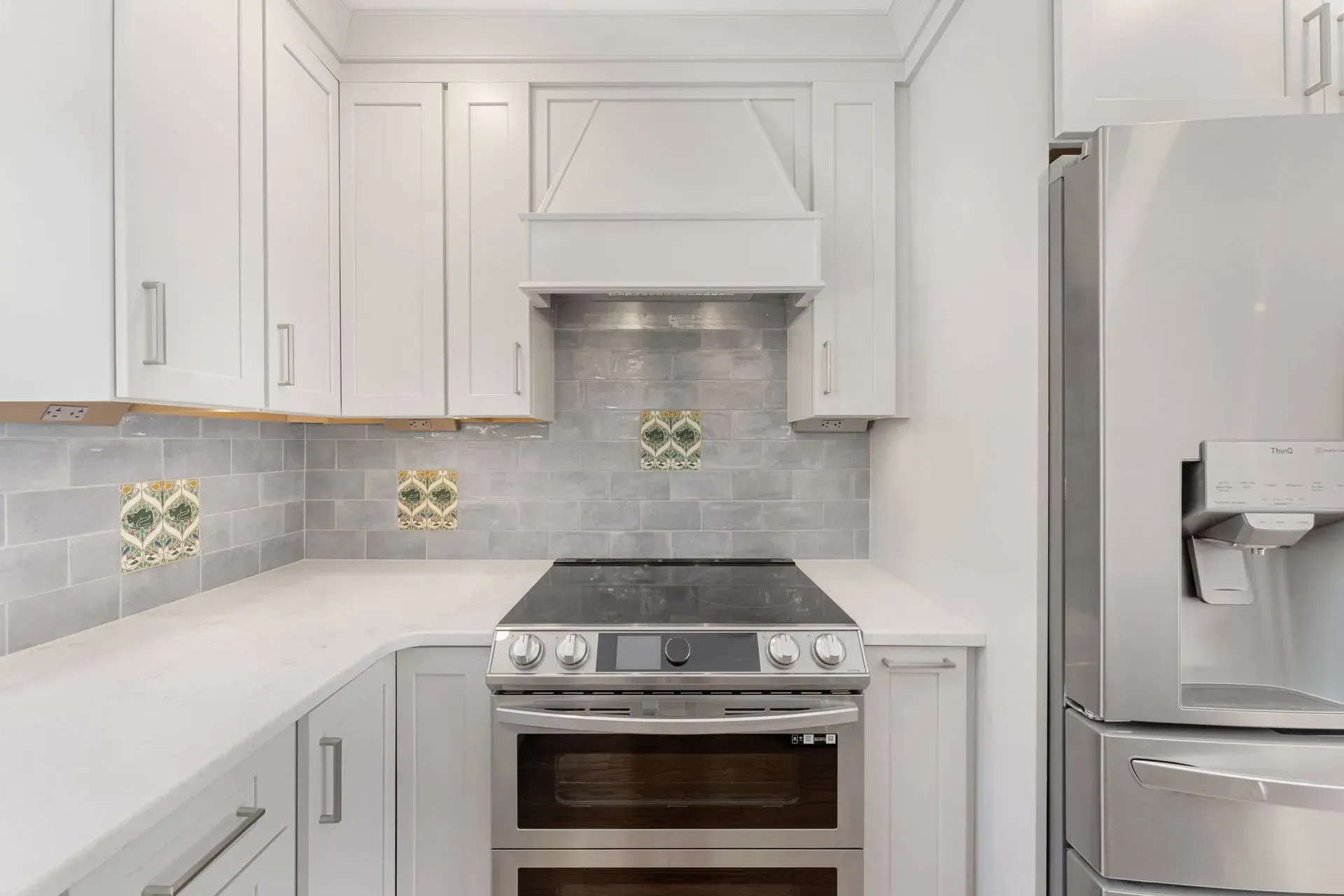 Bright white kitchen with stainless steel stove, fridge, and gray tile backsplash  In Bucks County PA