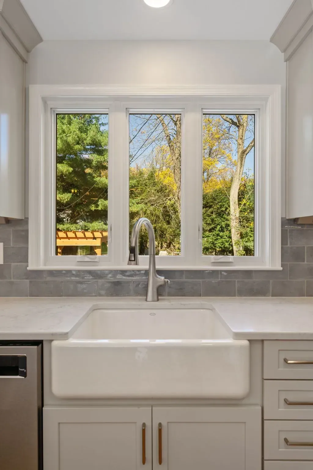 White kitchen sink beneath a window with garden view and chrome faucet  In Bucks County PA