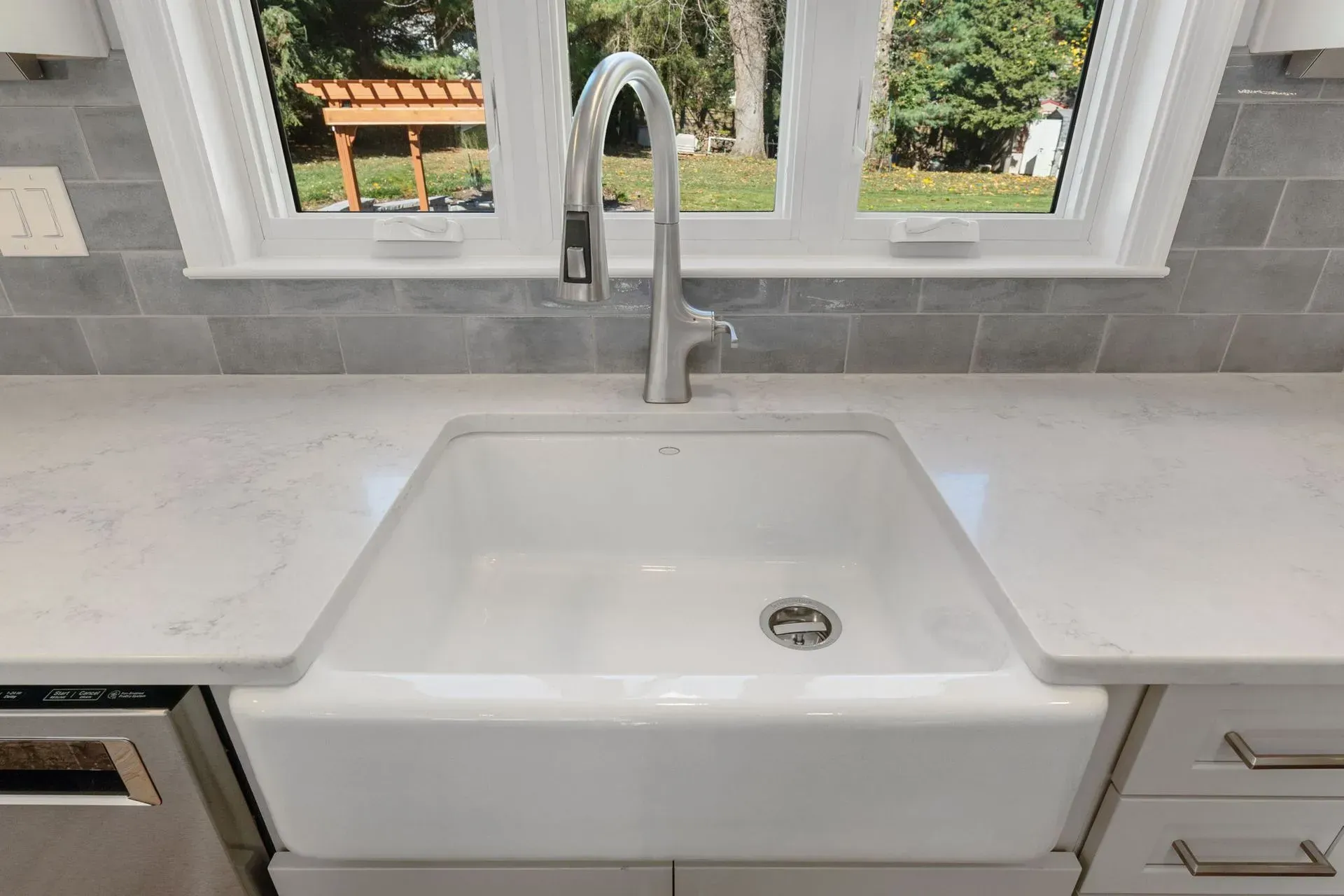 White farmhouse sink with chrome faucet in a bright kitchen by a window  In Bucks County PA