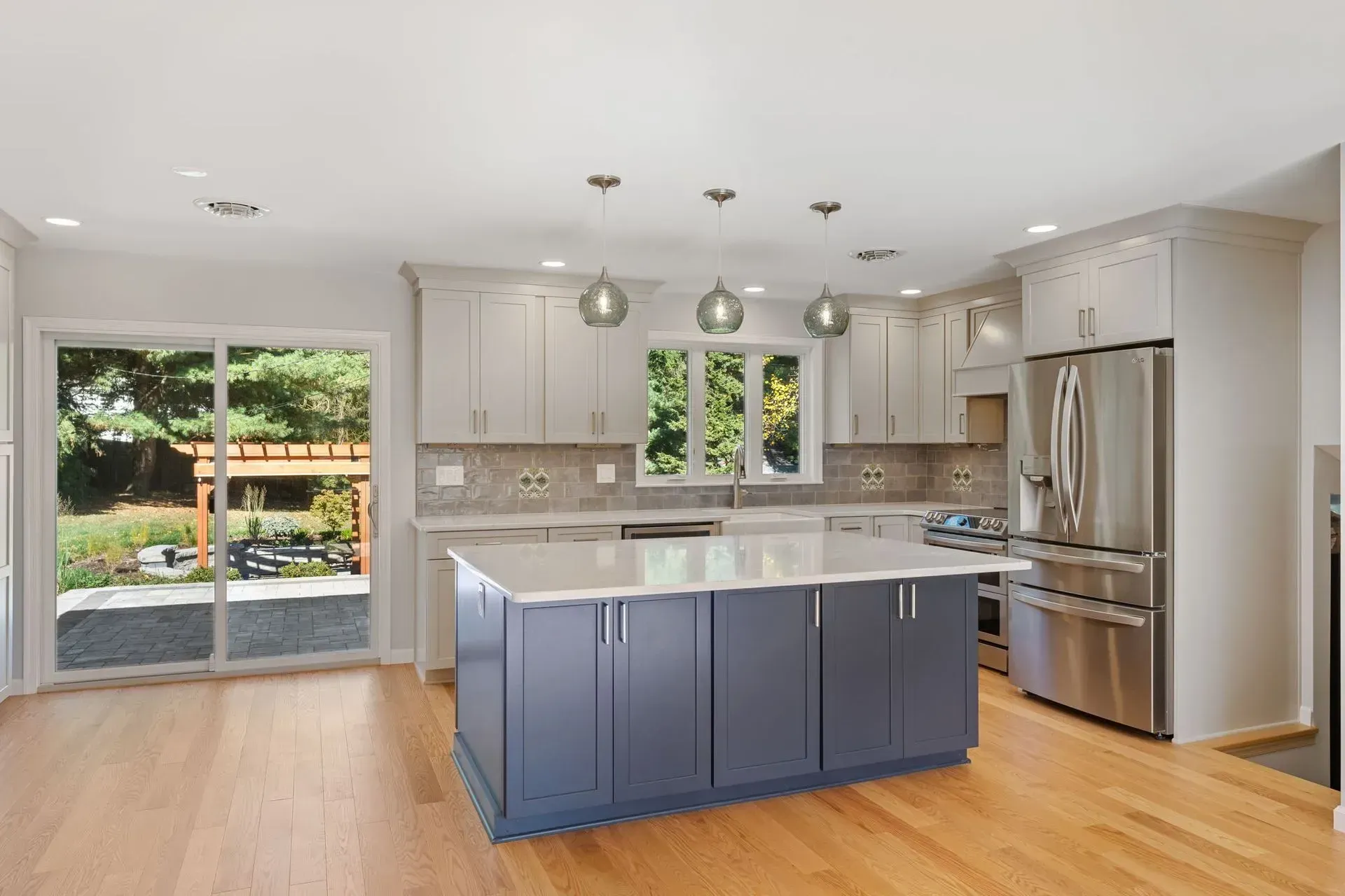 Bright modern kitchen with blue island, stainless steel appliances, and sliding glass doors to a patio  In Bucks County PA