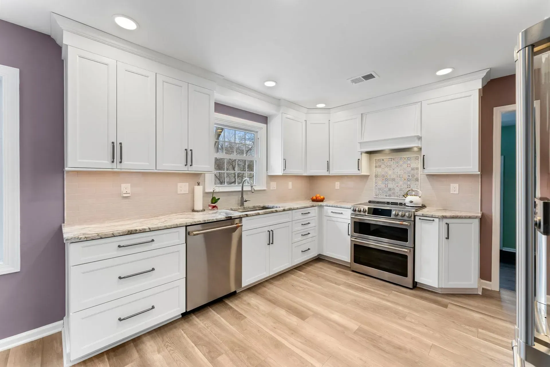 Bright modern kitchen with white cabinets, stainless appliances, and light wood floors In Bucks County PA