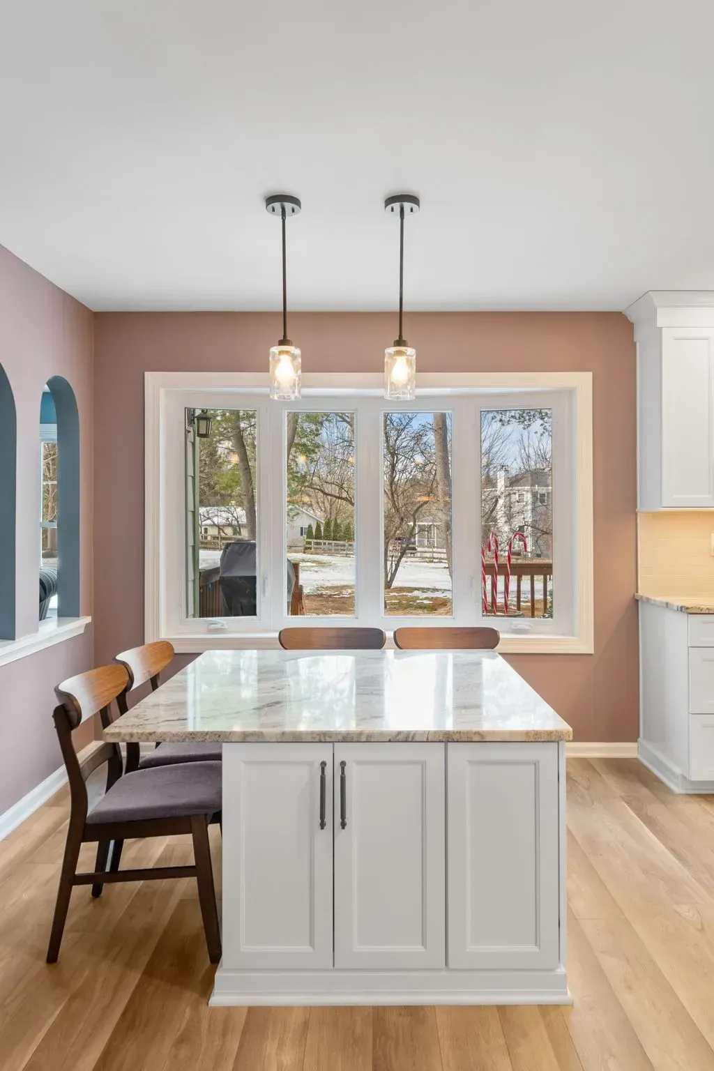 Bright kitchen with white island, wood floors, bay windows, and two pendant lights In Bucks County PA