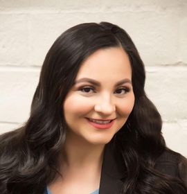 A woman with long dark hair is smiling for the camera